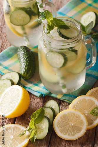 Soft drink with cucumber, lemon, ice and mint close up in a glass jar. vertical 