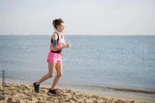 Young woman running across the beach. © gpointstudio