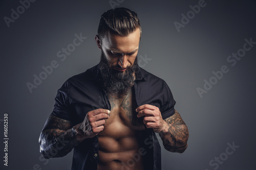 Tattooed bearded male taking off his shirt.