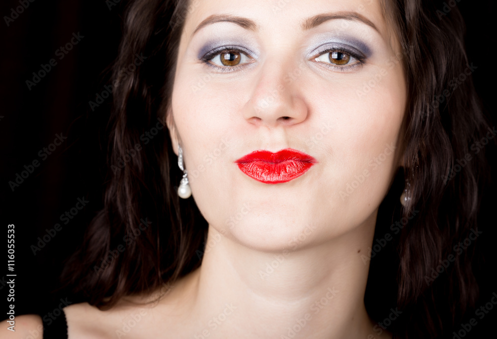 Close-up woman looks straight into the camera on a black background. expresses different emotions, sending a kiss Close-up woman looks straight into the camera on a black background. expresses different emotions, sending a kiss