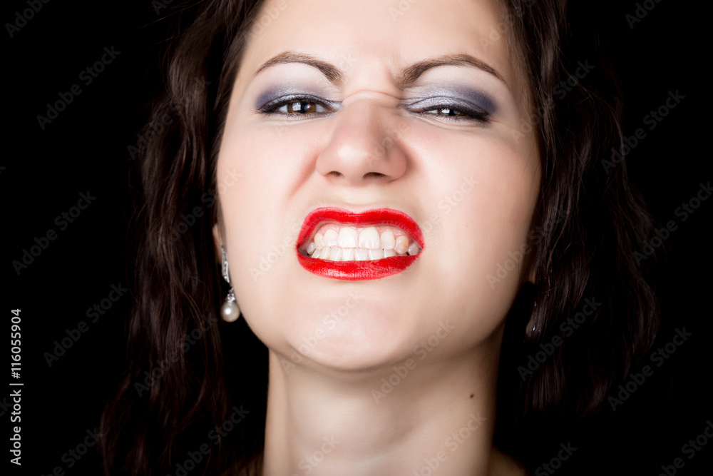 Close-up woman looks straight into the camera on a black background. expresses different emotions, showing teeth, showing grin growls Close-up woman looks straight into the camera on a black background. expresses different emotions, showing teeth, showing grin growls