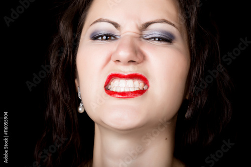 Close-up woman looks straight into the camera on a black background. expresses different emotions, showing teeth, showing grin growls