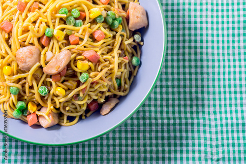 Valokuva Asian egg noodles with vegetables on green tablecloth.