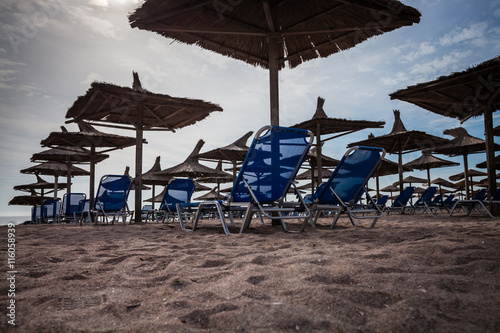 Color picture of straw beach umbrella and beach chairs