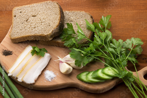Bread with lard, onion and parsley, garlic on a wooden surface.