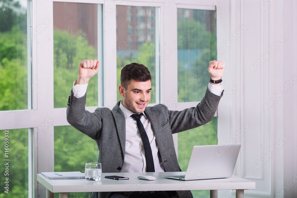 Businessman gets very good news on his computer monitor Businessman gets very good news on his computer monitor