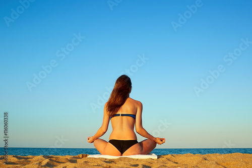 Young beautiful healthy woman doing meditation on the beach. Sum