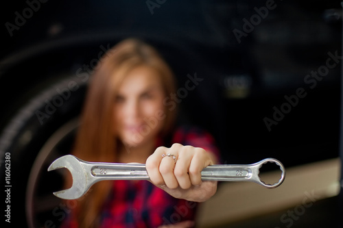 a young woman as a mechanic in a garage with wrench photo