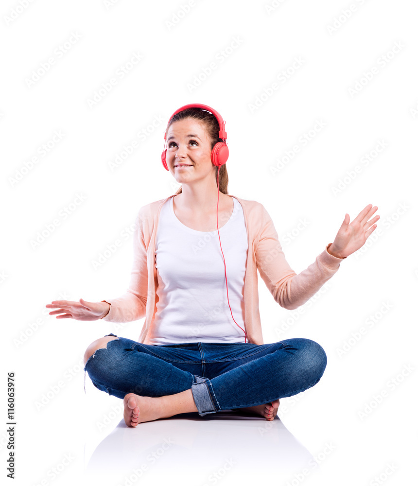 Woman with earphones sitting on the floor, studio shot, isolated Woman with earphones sitting on the floor, studio shot, isolated