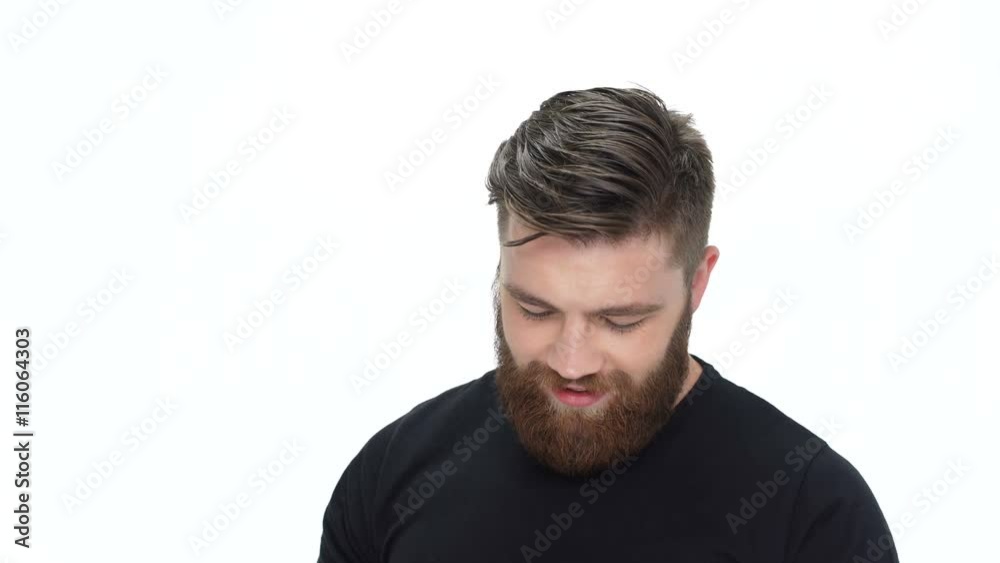 Young cute smiling bearded man showing lotion and using it Young cute smiling bearded man showing lotion and using it