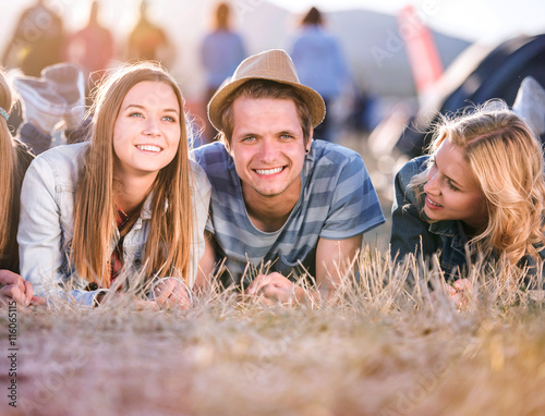 Teenagers lying on the ground in front of tents photo