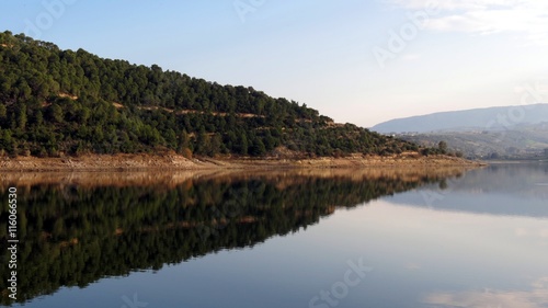 silhouette of forested hill in water © aadem