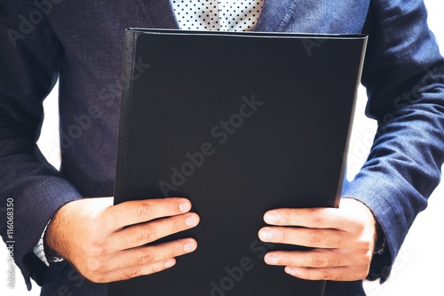 Businessman holding a black folder in hands photo