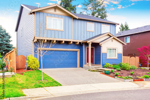 Nice curb appeal of blue house with front garden and garage with driveway