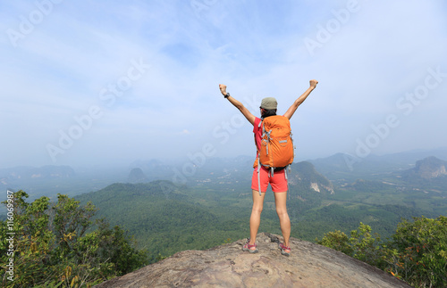 cheering young woman hiker enjoy the view on mountain peak cliff