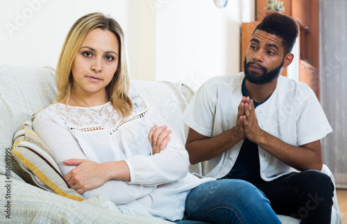 Indoors portrait of mixed couple trying to reconcile after quarr photo