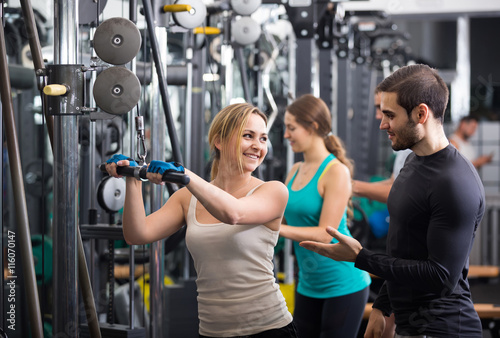 Adults having strength training under coach control in gym
