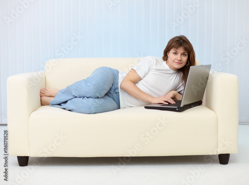 Beautiful young woman with laptop on sofa