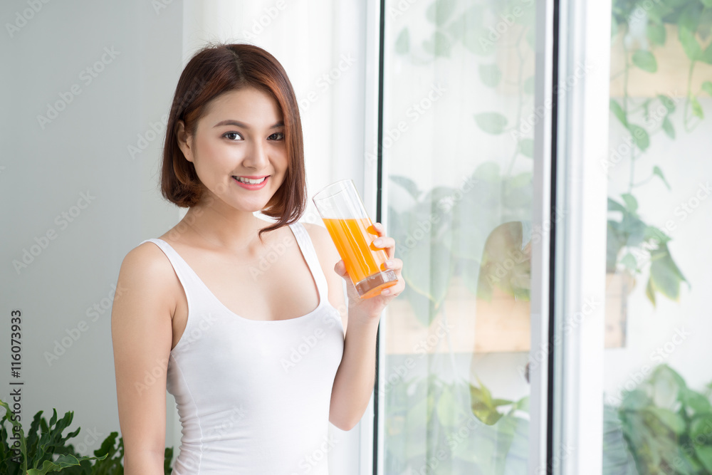 Pretty young asian woman in bright room drinking orange juice Pretty young asian woman in bright room drinking orange juice