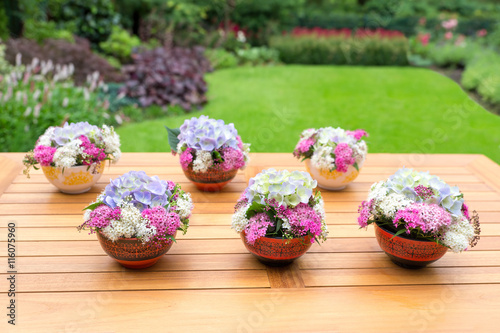 Vases with blooming flowers on teak table