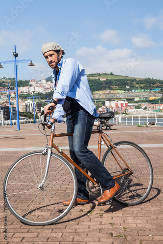 Happy middle-aged man with Irish beret bike riding enjoying a walk through the city
