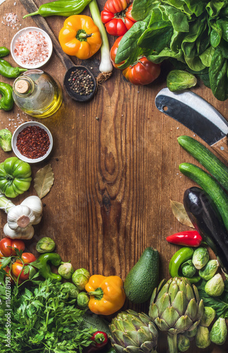 Fresh raw vegetable ingredients for healthy cooking or salad making on wooden background, copy space in center, top view. Diet , vegetarian food concept