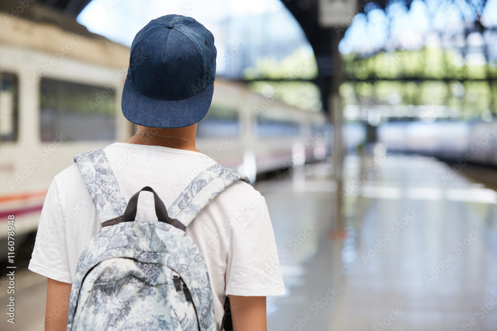 Back view of teenage school boy wearing white T-shirt and cap with a  backpack on