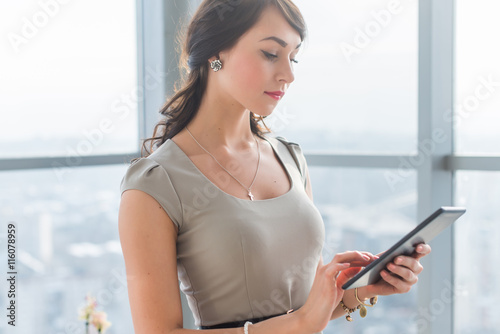 Close-up portrait of a young attractive freelancer using tablet for telework, typing and reading new messages on-line.