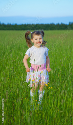 Happy child jumps on green grass in field photo