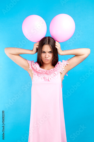Fotografi Angry girl with minnie mouse ears made of pink balloons