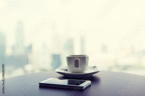 close up of smartphone and coffee cup on table