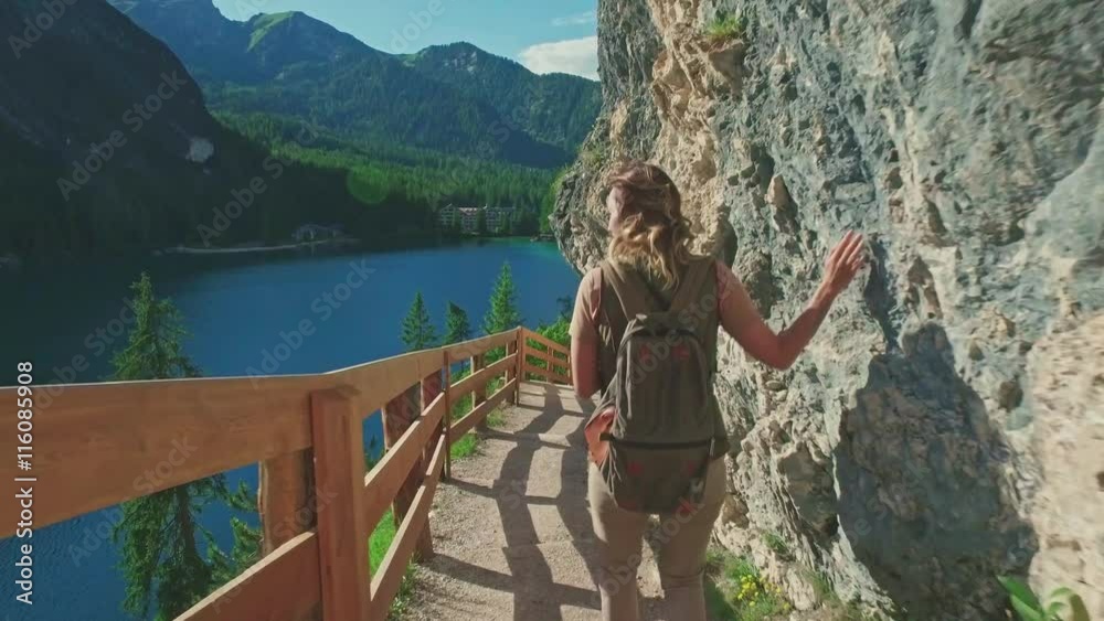 Woman hiker walking around the Braies lake and enjoys his spectacular sceneries, Dolomites, Italy