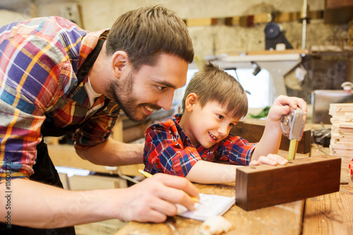dad and son with ruler measuring plank at workshop