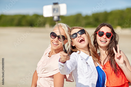 group of smiling women taking selfie on beach