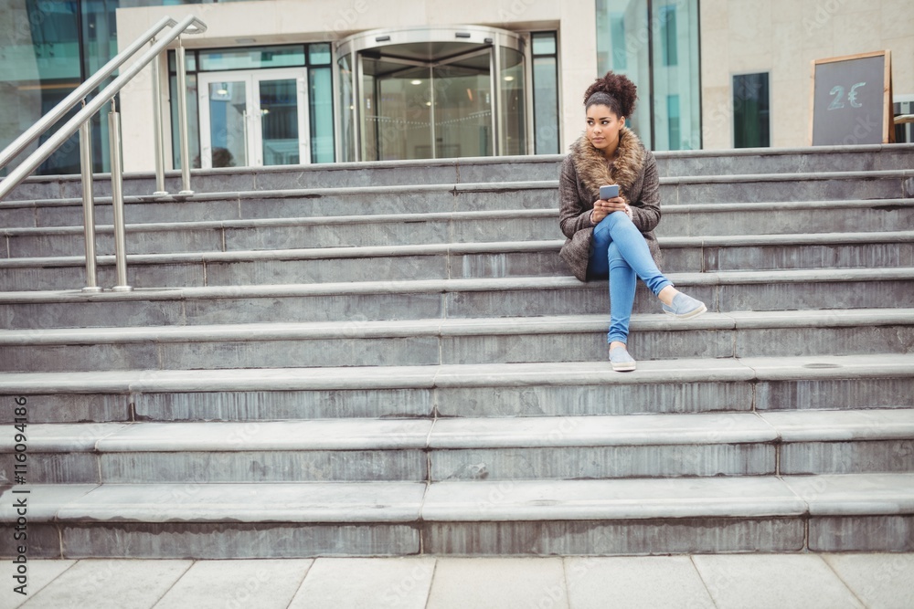 Woman holding phone while sitting on steps Woman holding phone while sitting on steps