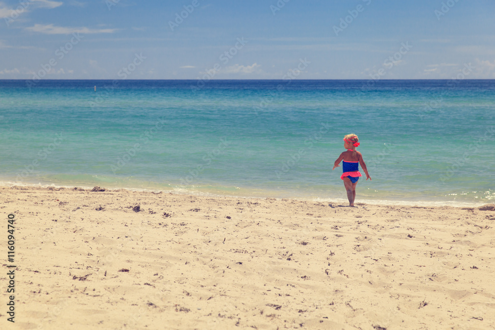 happy little girl going to swim at beach