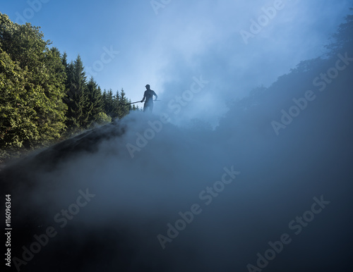 Traditional Charcoal Worker. Silhouette of wood charcoal maker at work on a pile of slow burning wood. This is the traditional way of producing charcoal.