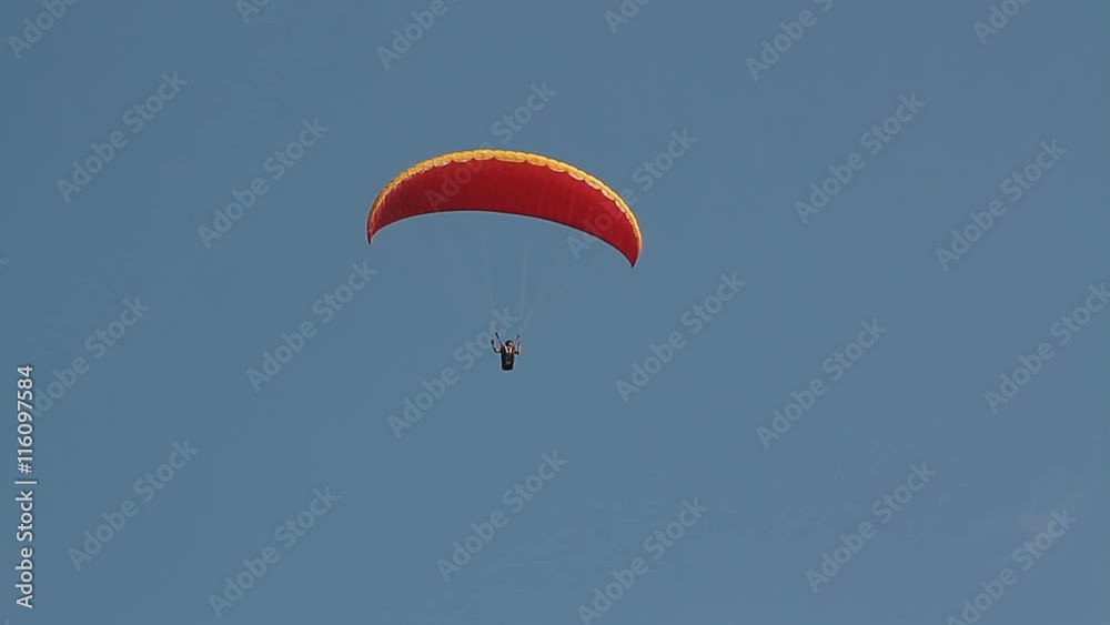 Paragliding over the mountains against clear blue sky Paragliding over the mountains against clear blue sky