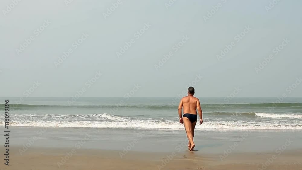 Happy young man swimming on the beach