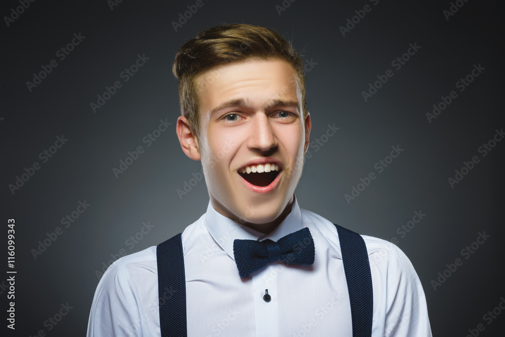 Closeup Portrait of handsome boy with astonished expression while standing against grey background Closeup Portrait of handsome boy with astonished expression while standing against grey background
