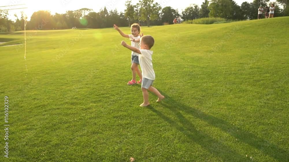 Active interesting games for small kids. unusual Funny soap bubbles. Two boy and girl playing on green summer field. Slow motion video footage. Contre-jour Backlight. Flares flecks of sunlight Active interesting games for small kids. unusual Funny soap bubbles. Two boy and girl playing on green summer field. Slow motion video footage. Contre-jour Backlight. Flares flecks of sunlight