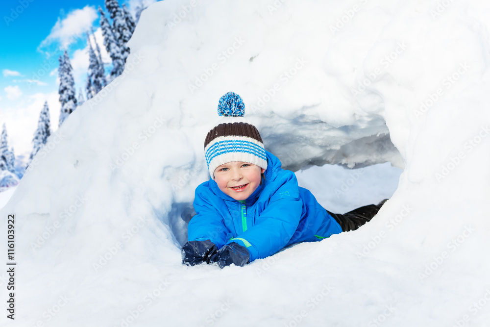 Little boy crawl through snow tunnel in park