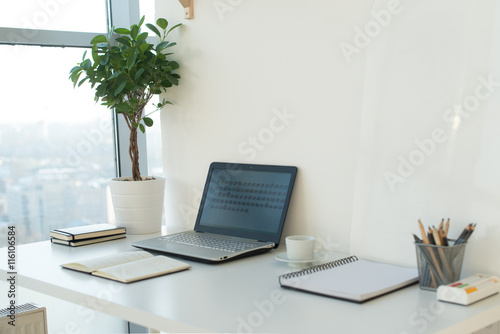 Картината върху платно Side view picture of studio workplace with blank notebook, laptop