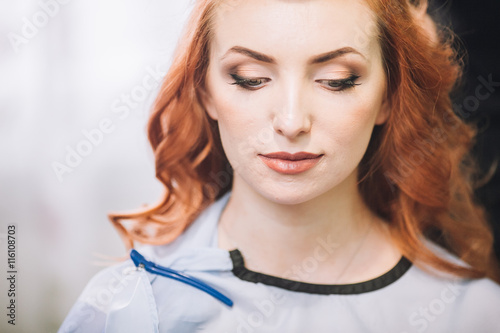 Makeup artist preparing bride before the wedding in a morning. Red hair woman. Hairdresser.