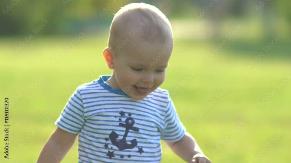 Happy kid running on the camera on the green grass and smiling Happy kid running on the camera on the green grass and smiling