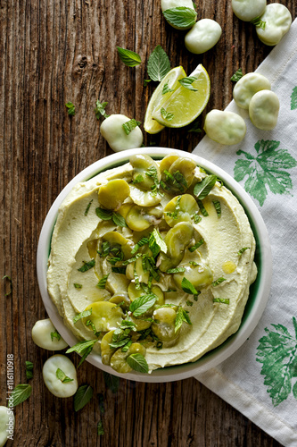 Broad bean hummus with addition of olive oil and fresh mint on plate,  top view