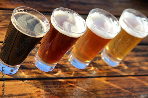 Four glasses of different craft beers on a wooden table during a tasting