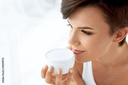 Fototapeta Naklejka Na Ścianę i Meble -  Skin Care. Beautiful Happy Woman Holding Face Cream Lotion
