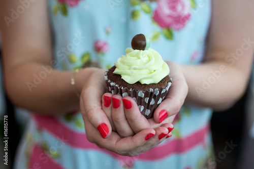 Woman with red painted nails holding pretty mint chocolate cupca