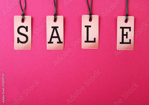 Paper tags with strings on pink background. Sale concept
